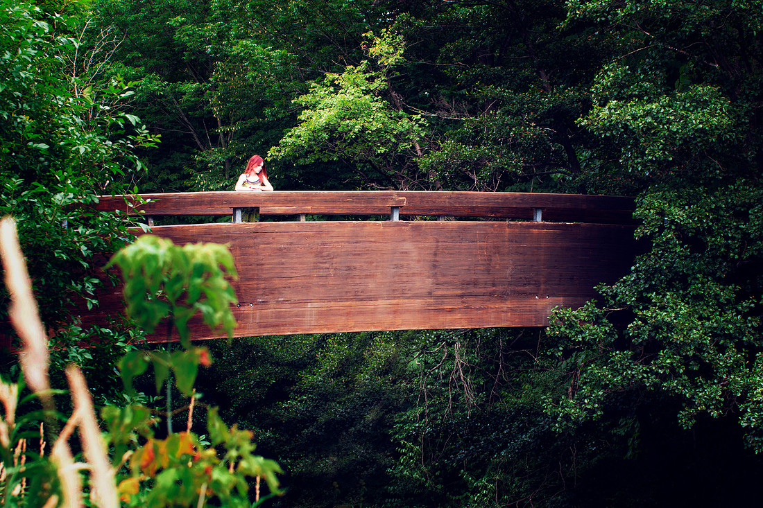 Portrait photograph of a girl on a wooden bridge in the forest.