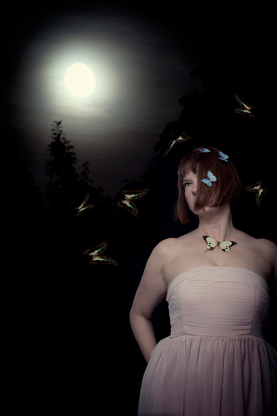 Surreal portrait of woman with butterflies under a full moon.