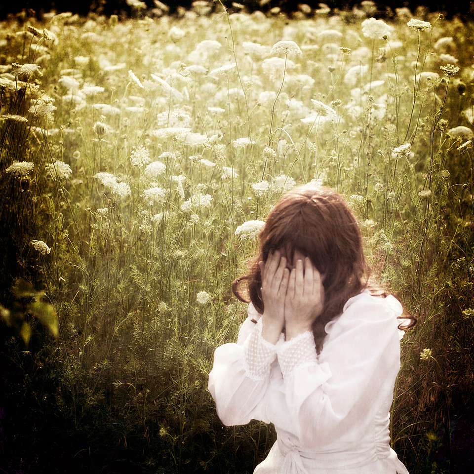 photograph of woman with face covered in a field of Queen Anne's Lace
