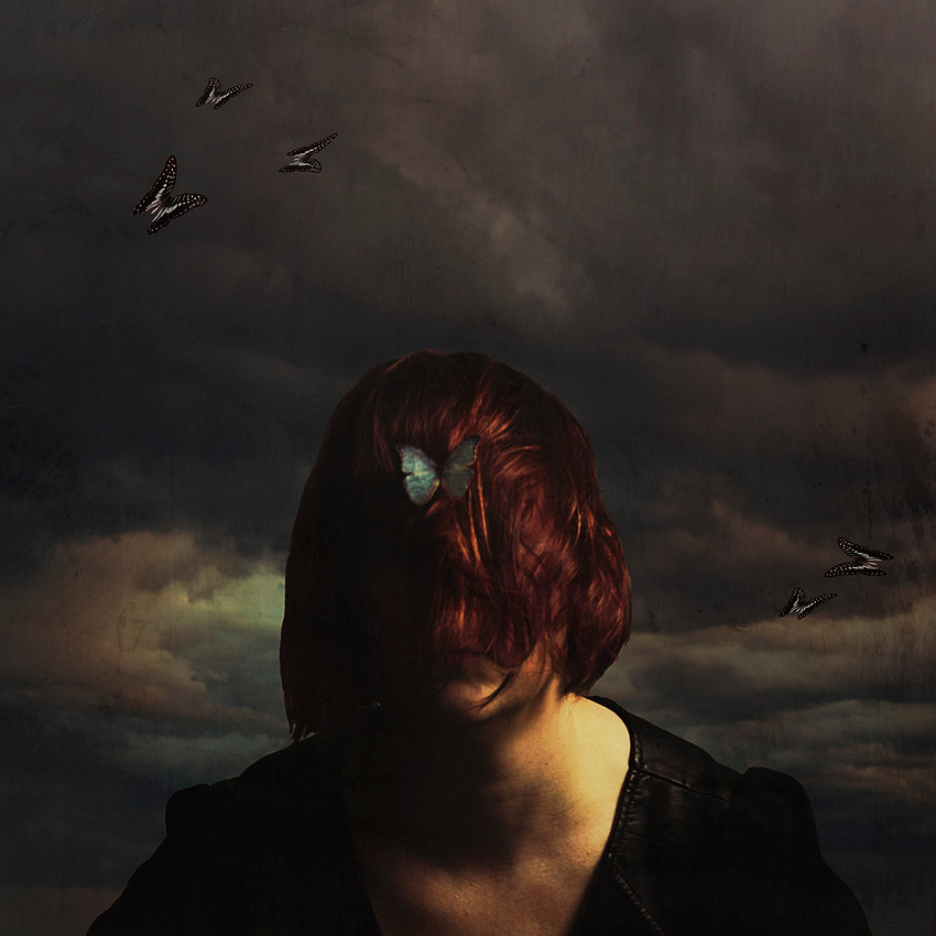 Surreal portrait photo with stormy sky and blue butterfly