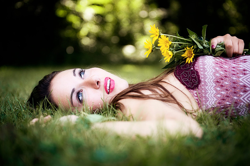Woman laying on back in grass with flowers