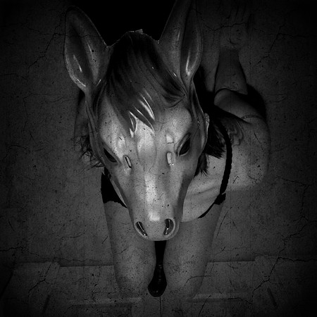 Black and white photograph of a woman in a horse mask
