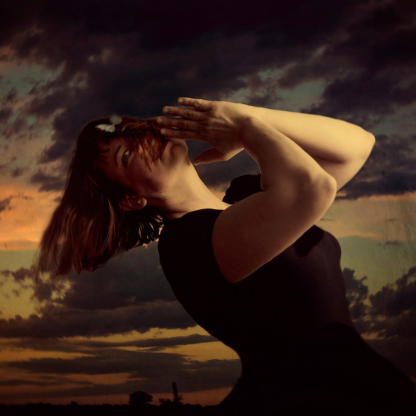 portrait photograph of woman praying against a sunset