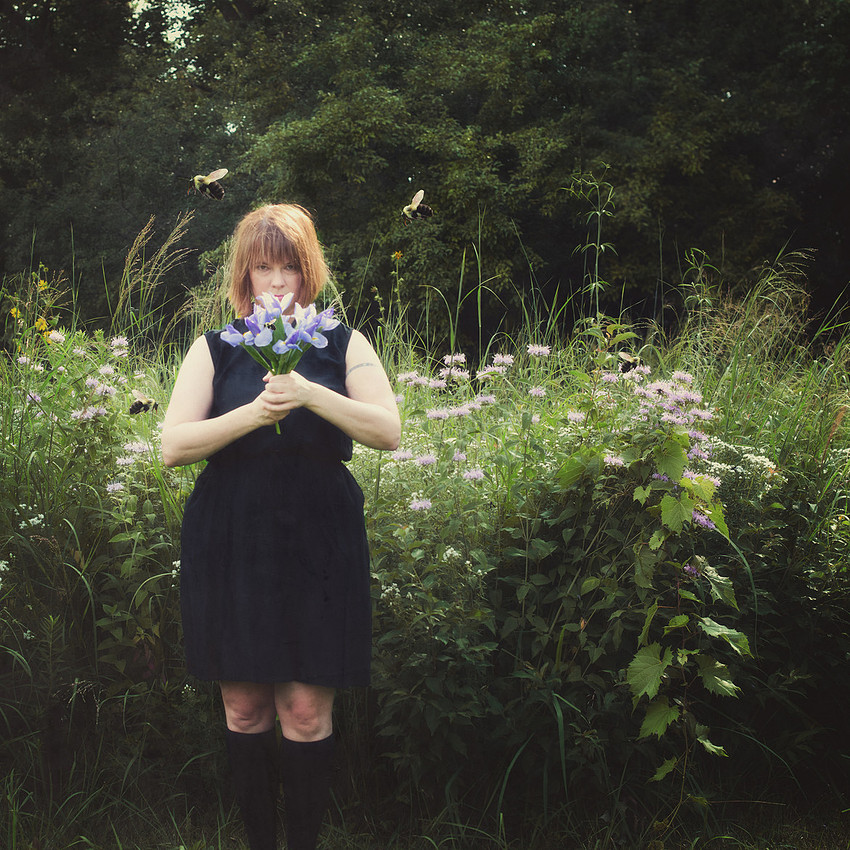 portrait, woman surrounded by bumble bees holding irises