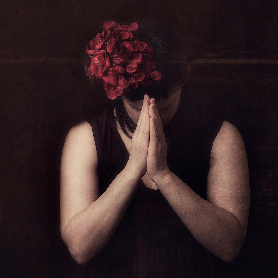 Portrait photograph woman in prayer pose.