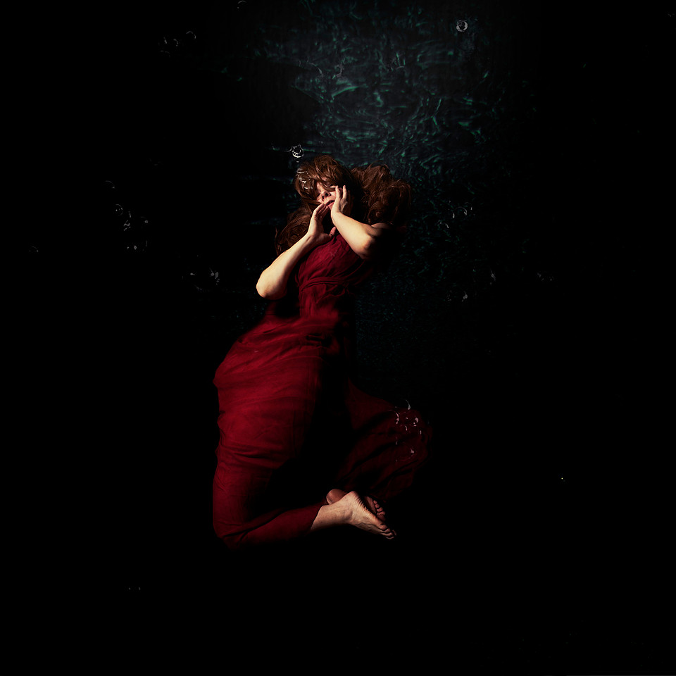 Woman in red dress under dark water