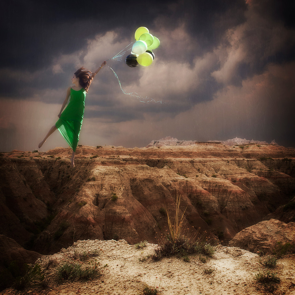 woman holding green balloons floating across the Badlands